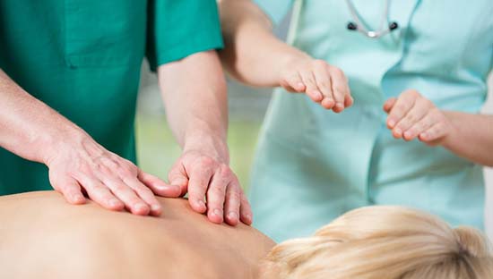 Experienced physiotherapist correcting the student during massage